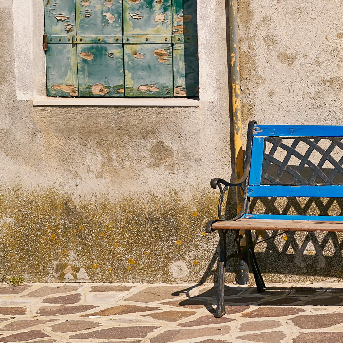 Blue bench against a textured wall with peeling paint