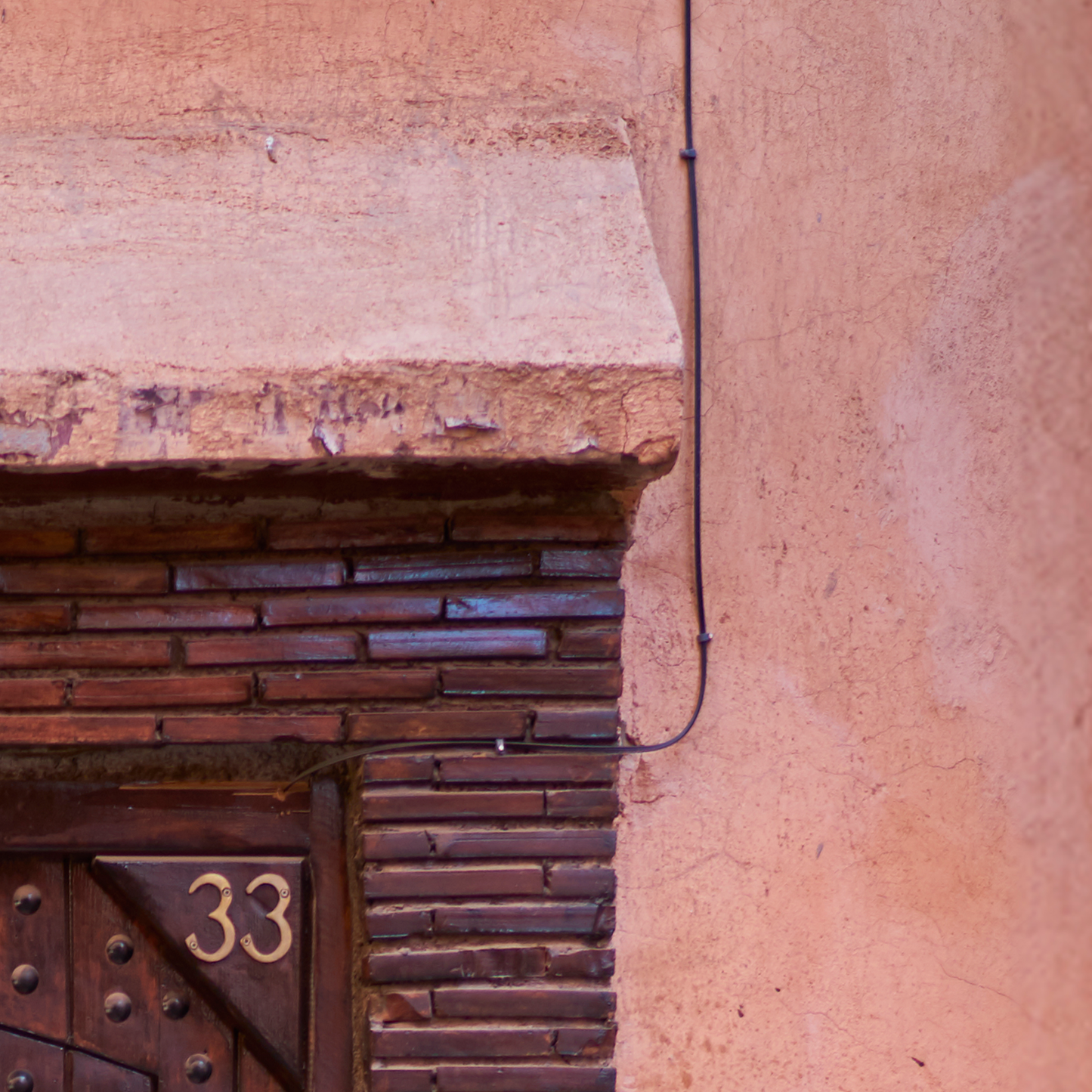 Close-up of a textured wall with a door number '33' on a building.