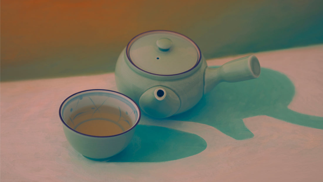 Photograph of a Chinese tea pot and cup sitting on a painted table and background