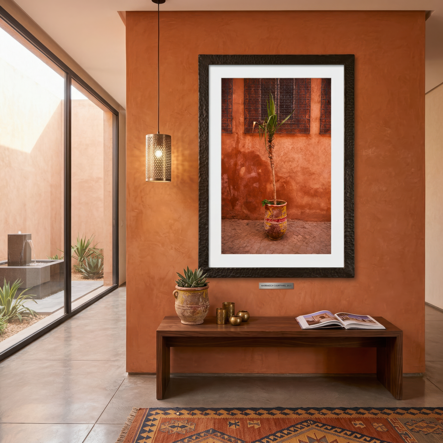 Framed photograph of a plant in Marrakesh on an orange wall with a wooden bench and decor items.