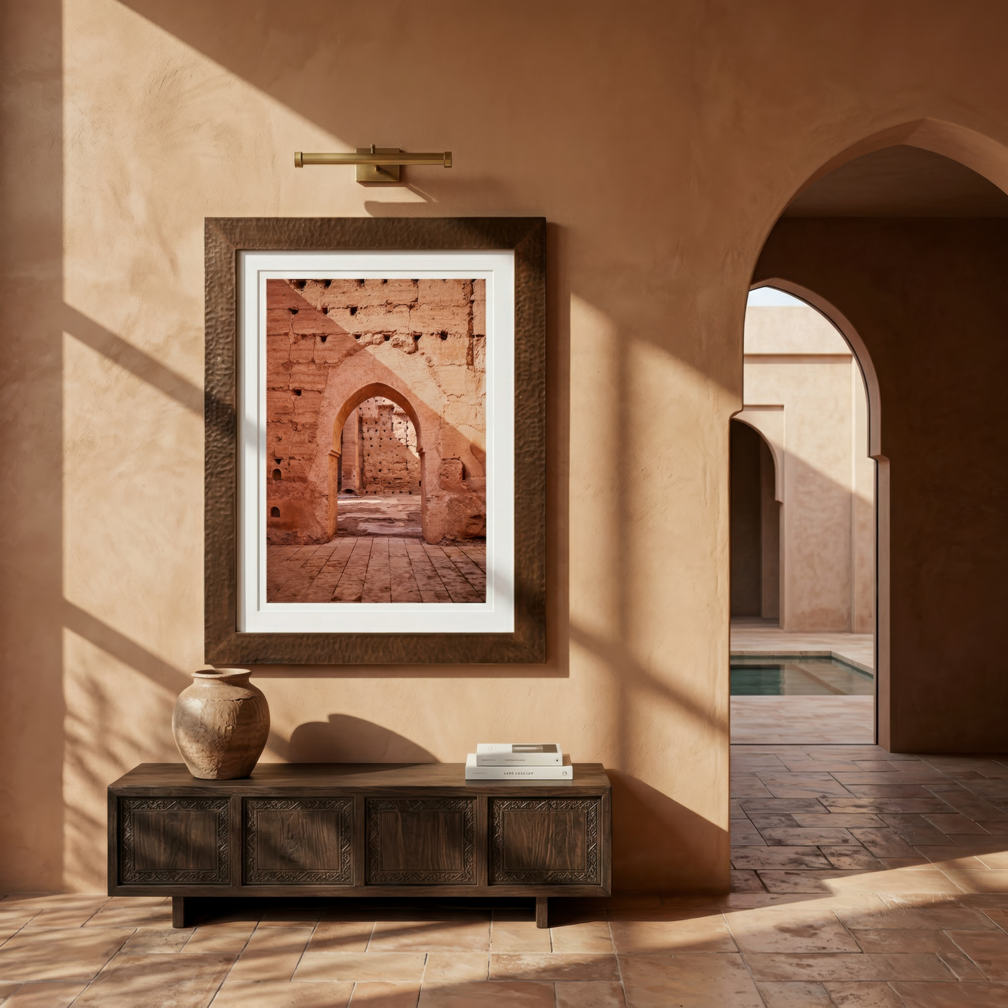 Framed photograph of an architectural scene in Marrakesh on a wall in a sunlit room with a wooden cabinet.