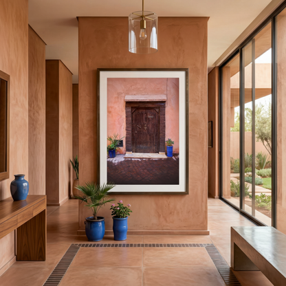 Modern interior with a large framed photograph of Marrakesh on a wall, featuring a door and plants.