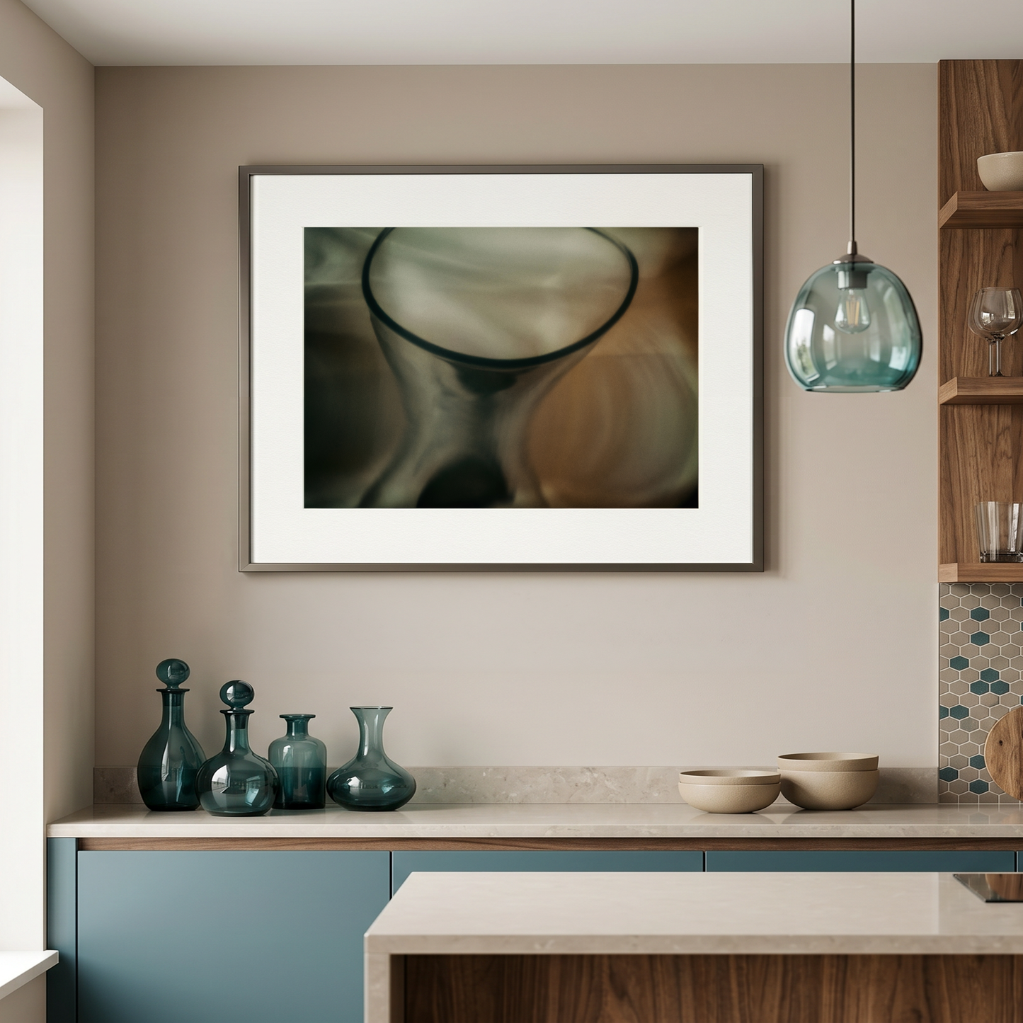 Modern kitchen interior with framed artwork, glassware, and pendant light.