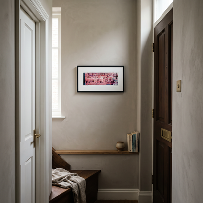 A framed panoramic abstract art print in pink, purple and black tones, displayed on a wall in a styled interior setting.
