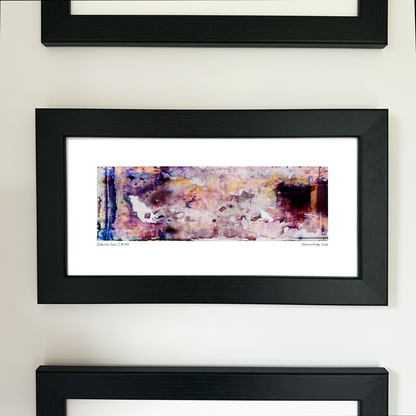 A framed abstract art print with a black frame and white mat, featuring Naturalia II #008 in pink, purple and blue tones, mounted on a white wall.
