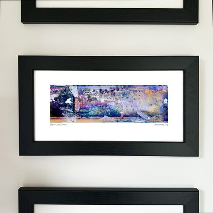 A framed abstract art print with a black frame and white mat, featuring Naturalia II #009 in blue, purple and peach tones, mounted on a white wall.
