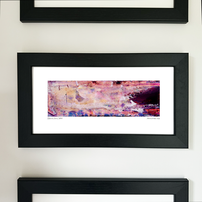 A framed abstract art print with a black frame and white mat, featuring Naturalia II #010 in pink, peach and purple tones, mounted on a white wall.
