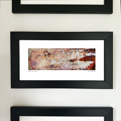 A framed abstract art print with a black frame and white mat, featuring Naturalia II #012 in pink, peach and orange tones, mounted on a white wall.
