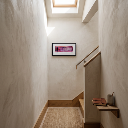 A framed panoramic abstract art print in pink, purple and burgundy tones, displayed on a wall in a styled interior setting.
