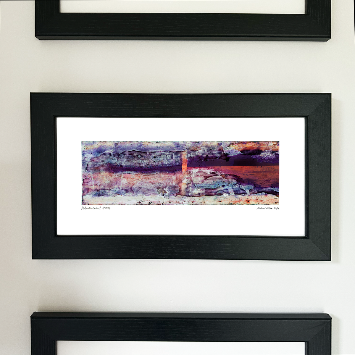 A framed abstract art print with a black frame and white mat, featuring Naturalia II #024 in purple, pink and orange tones, mounted on a white wall.
