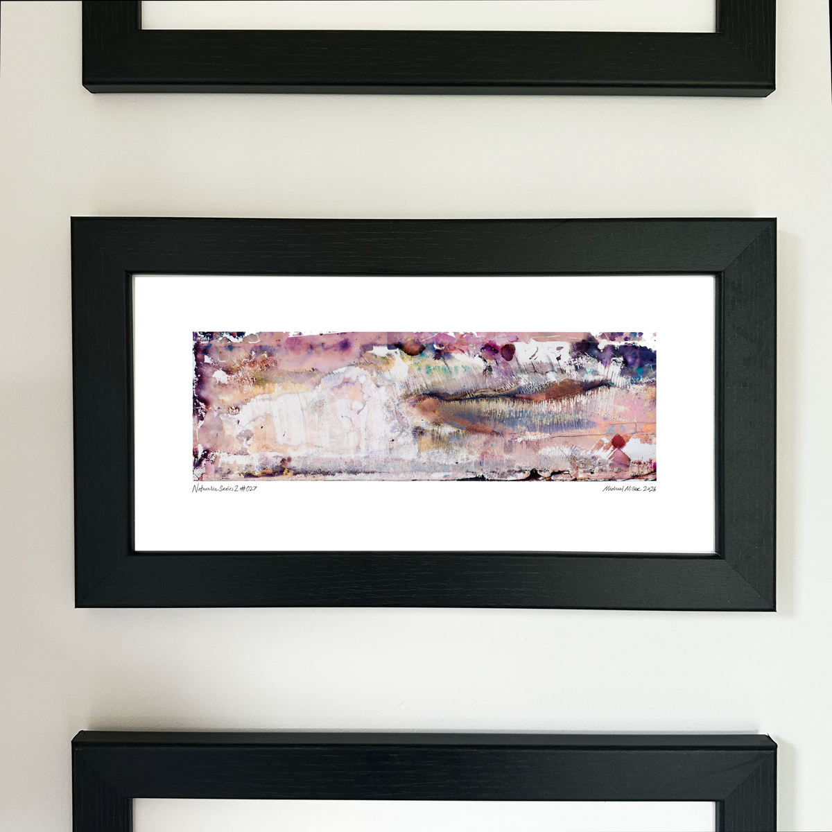 A framed abstract art print with a black frame and white mat, featuring Naturalia II #027 in pink, purple and peach tones, mounted on a white wall.
