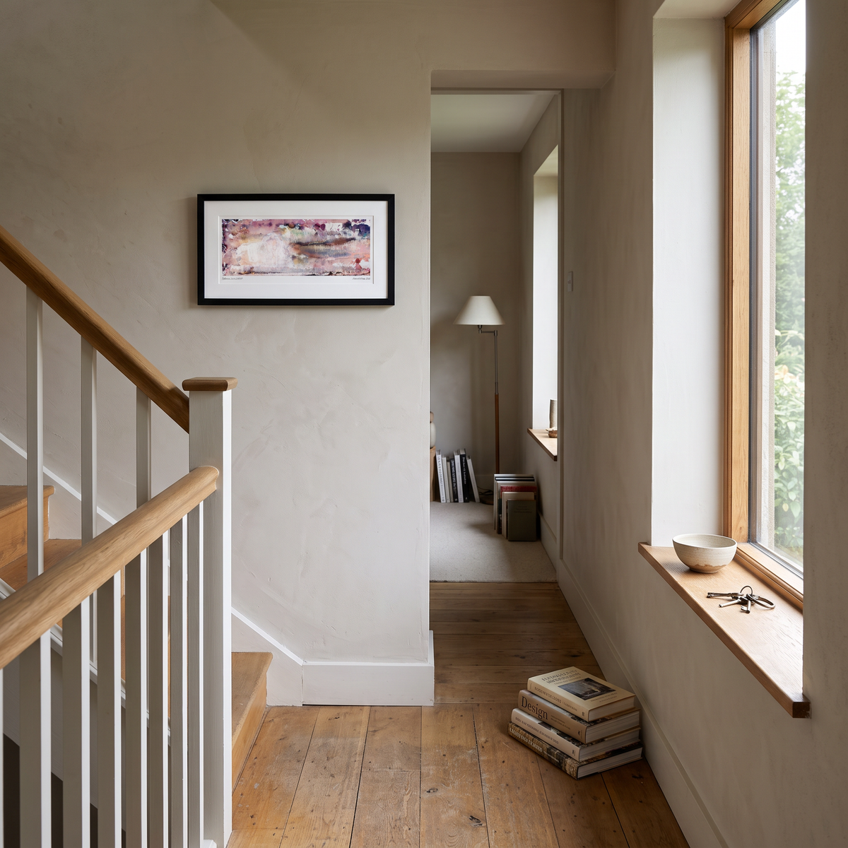 A framed panoramic abstract art print in pink, purple and peach tones, displayed on a wall in a styled interior setting.
