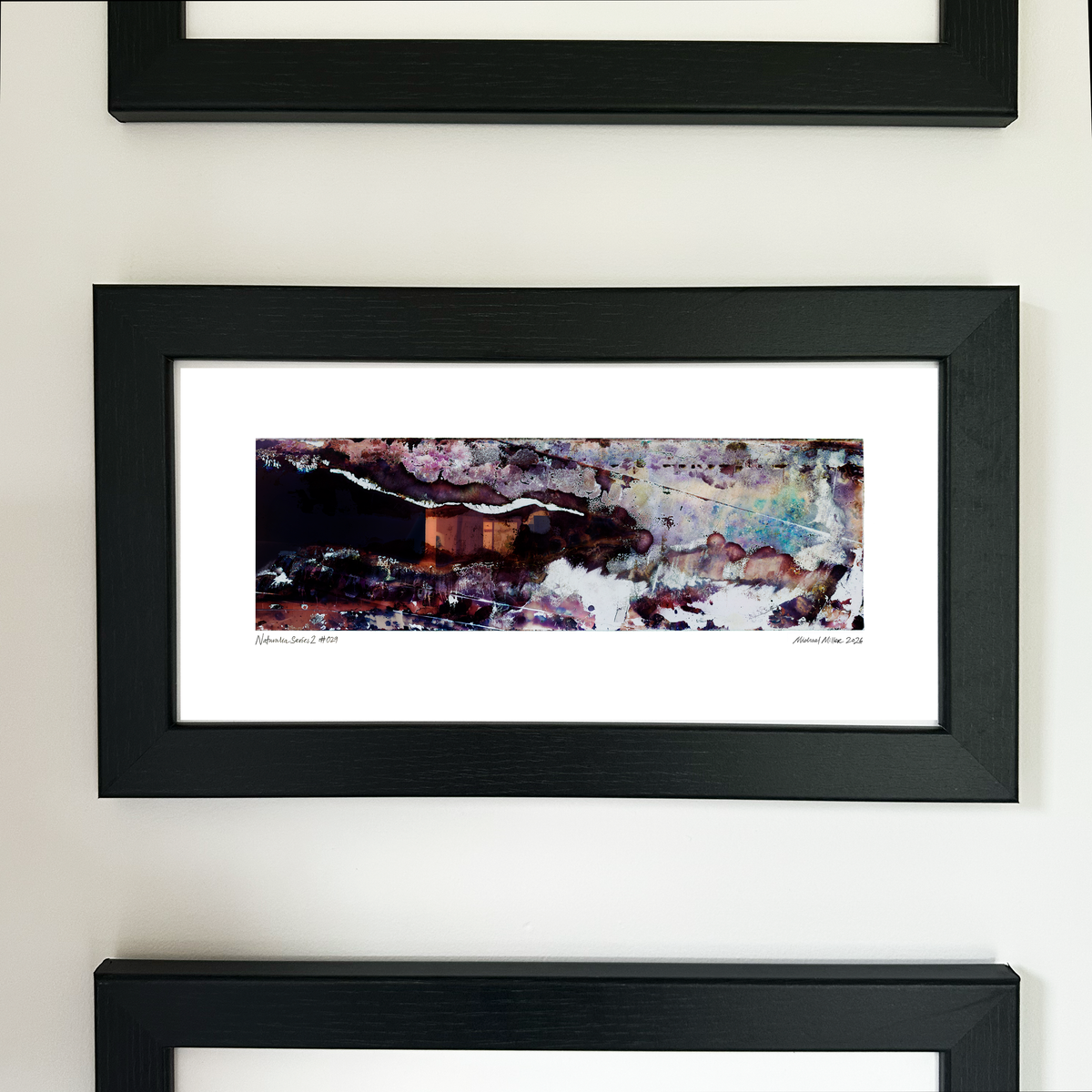 A framed abstract art print with a black frame and white mat, featuring Naturalia II #029 in black, purple and blue tones, mounted on a white wall.
