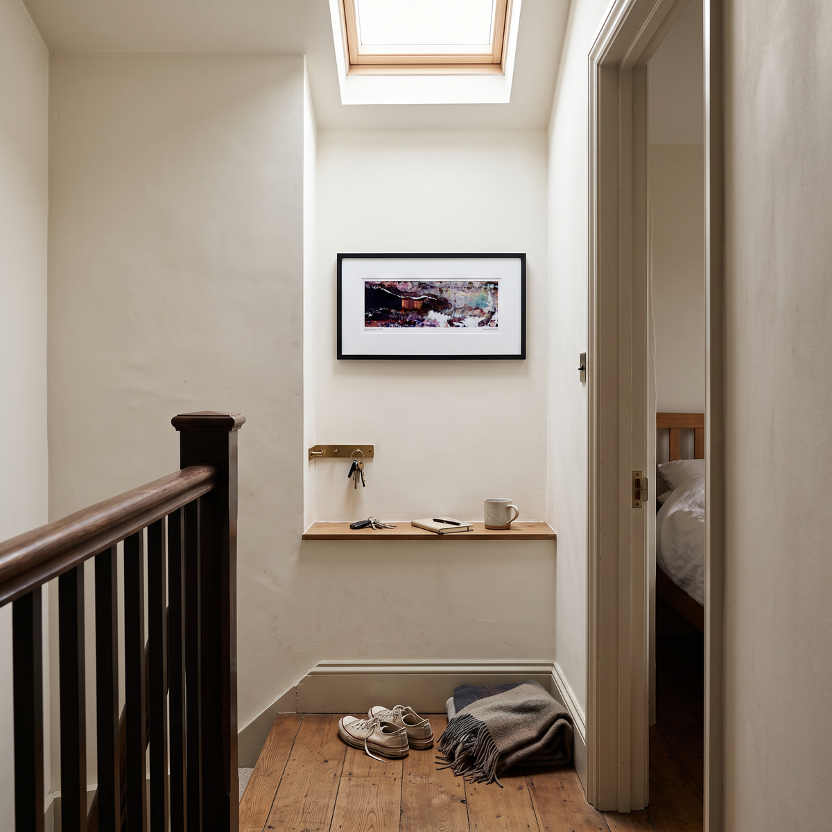 A framed panoramic abstract art print in black, purple and blue tones, displayed on a wall in a styled interior setting.
