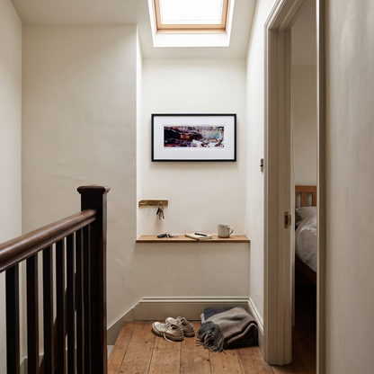 A framed panoramic abstract art print in black, purple and blue tones, displayed on a wall in a styled interior setting.

