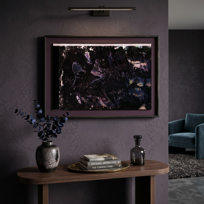 Framed abstract artwork on a dark wall with decorative items on a wooden console table.