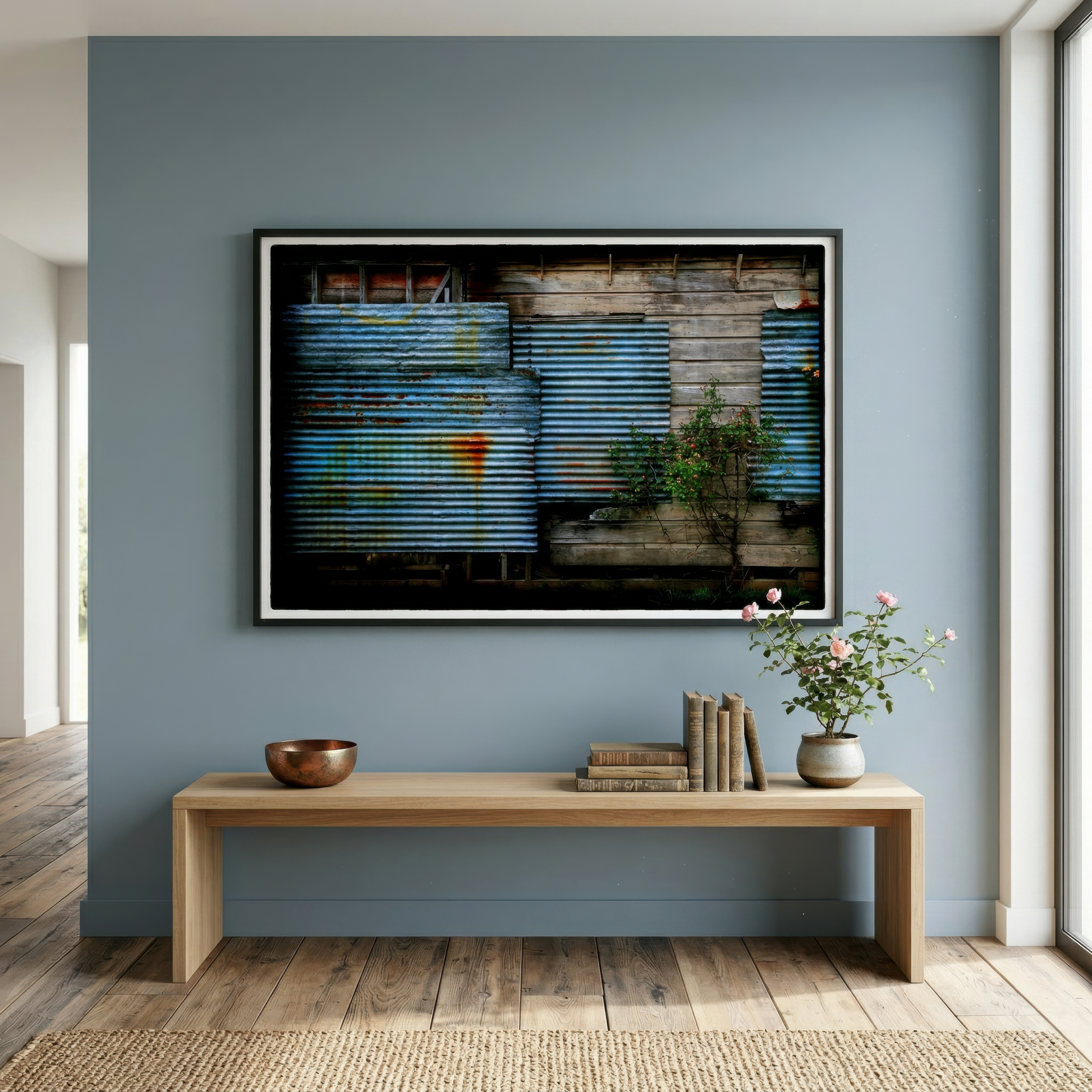Framed photograph of a corrugated wall on a blue wall above a wooden bench with decor items.