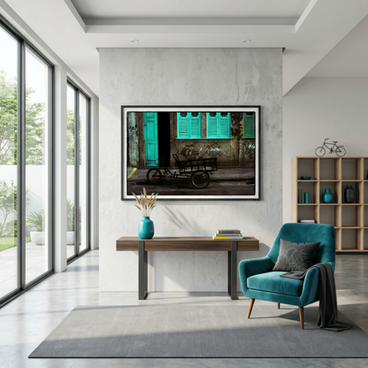 Modern interior with a teal chair, wooden desk, and framed photograph of a Rio street on a gray wall.