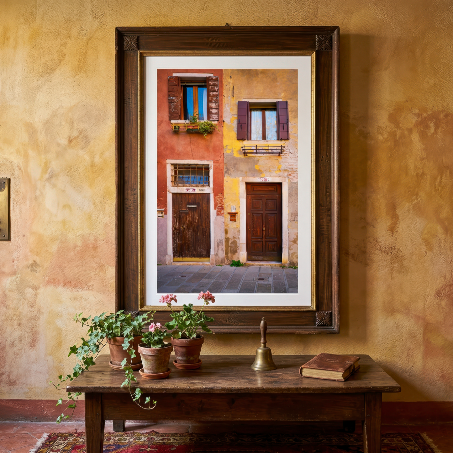 Framed photograph of two Venice doorways on a textured wall above a wooden table with plants.