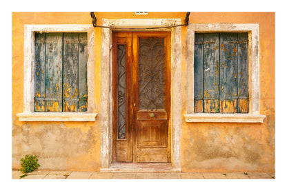 Wooden door with two windows on a yellow wall in Venice Italy