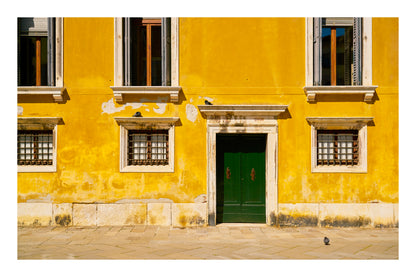 Yellow building facade with a green door and windows in Venice Italy