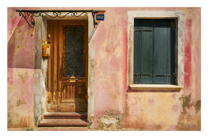 Vintage building facade with a wooden door and window with metal bars.