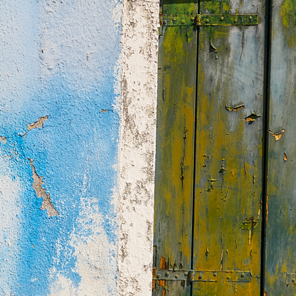 Rustic wooden door with peeling paint next to a blue wall.
