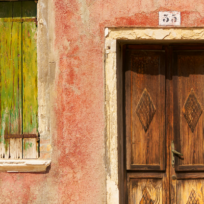 Wooden door with decorative patterns on a weathered building facade.
