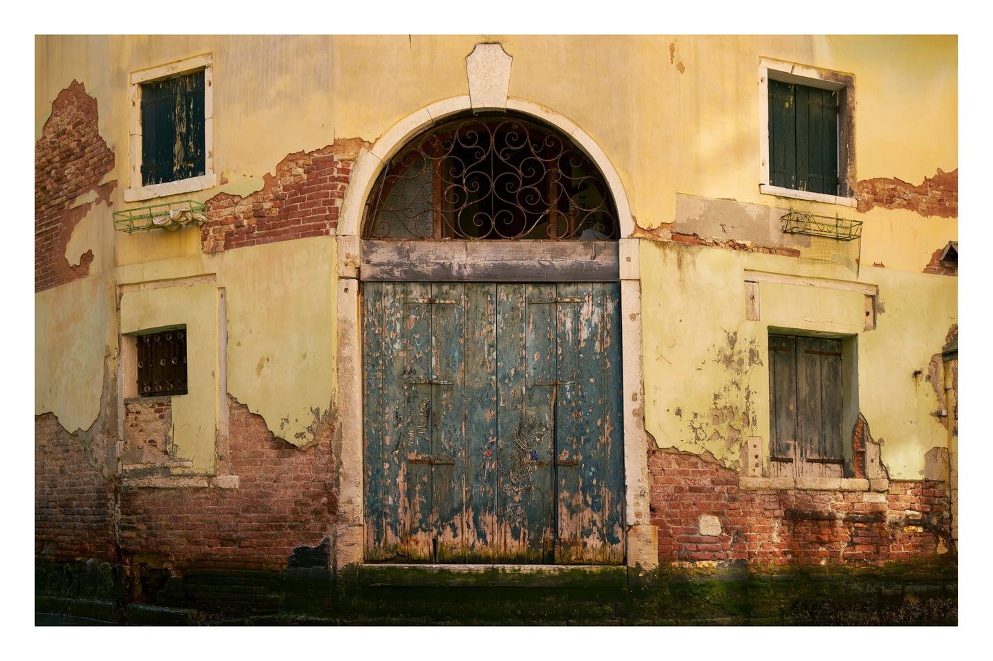 Old, weathered building facade with a large door and windows showing signs of decay.