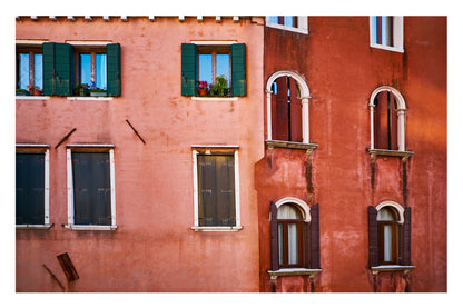 Red brick building with green shutters and arched windows in Venice, Italy.