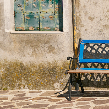 Blue bench against a textured wall with peeling paint