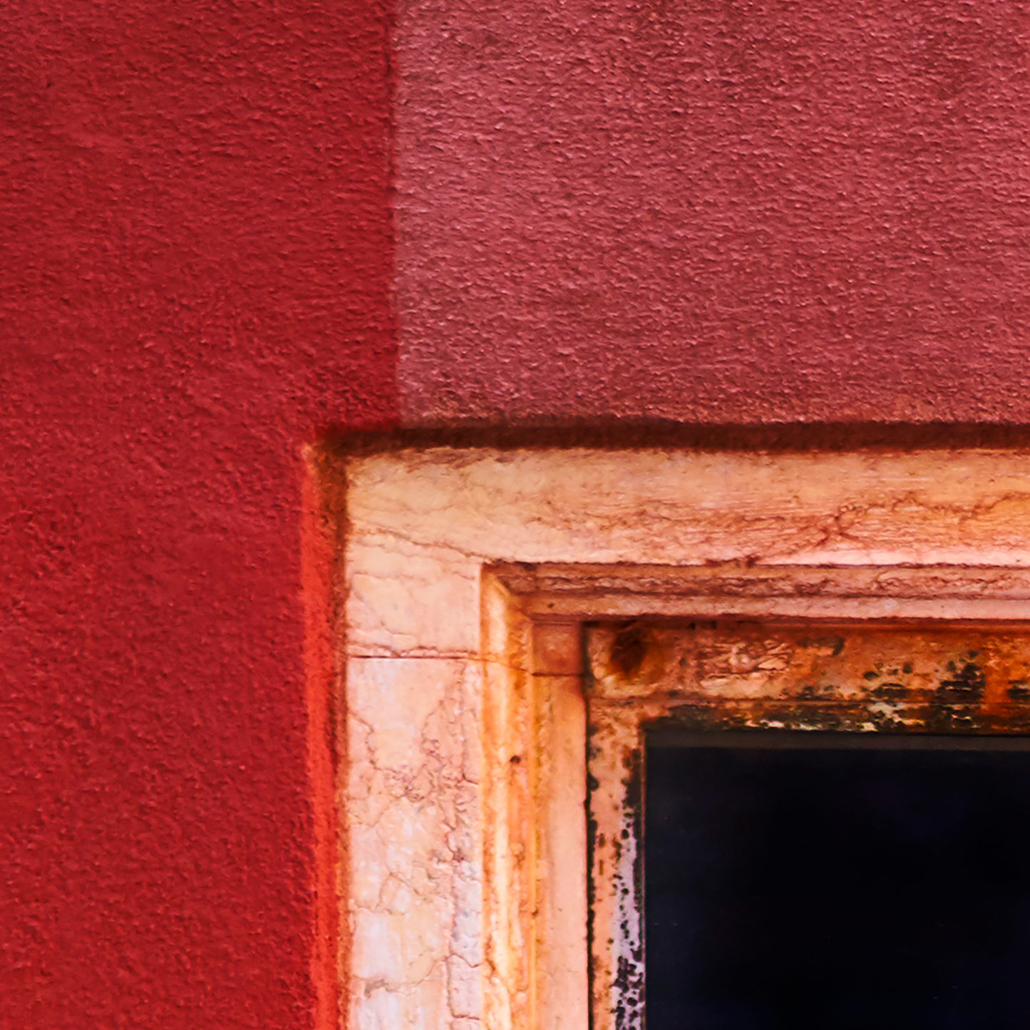 Close-up of a textured red wall with a wooden frame