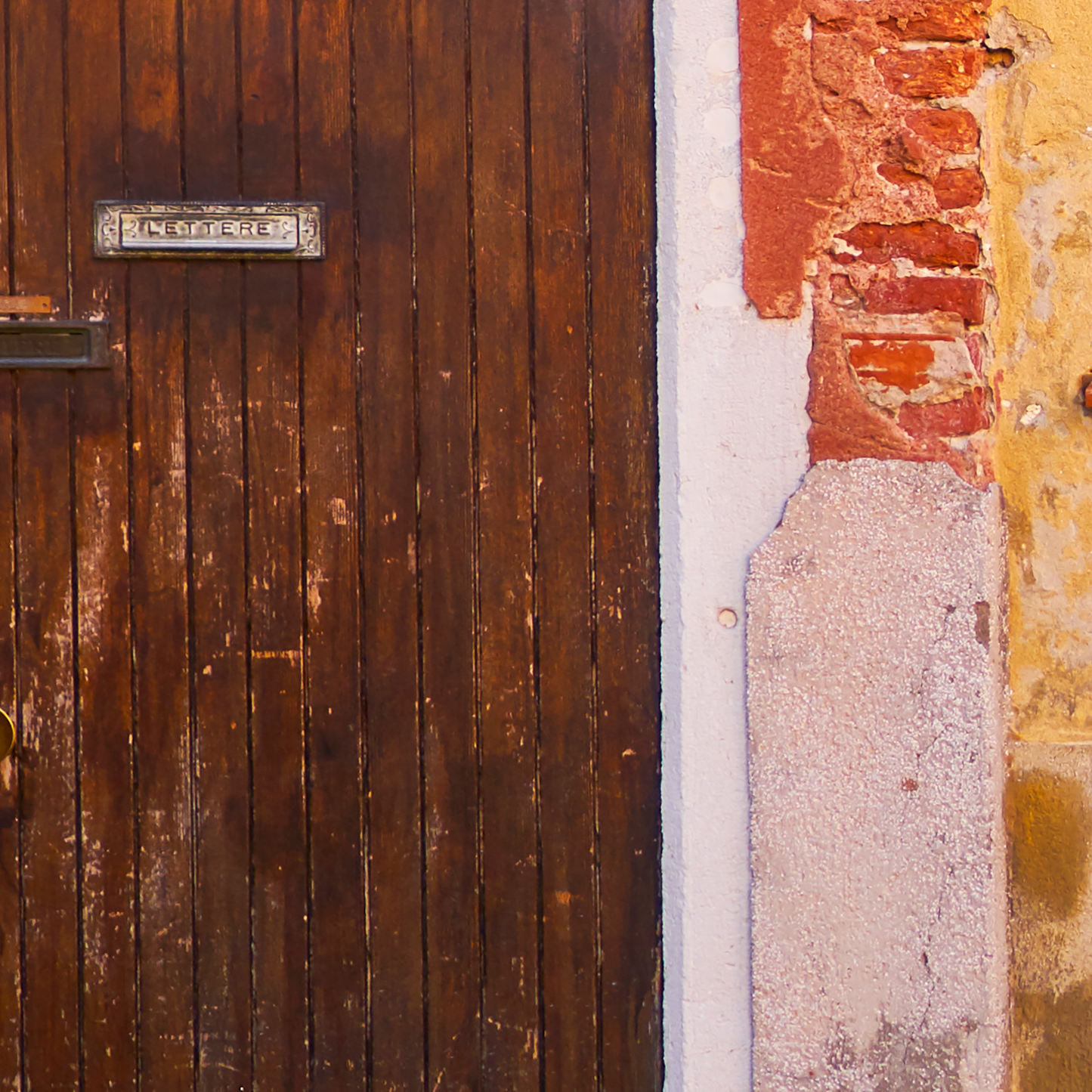 Close-up of a wooden door with a metal handle and a textured wall.