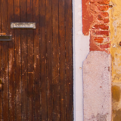 Close-up of a wooden door with a metal handle and a textured wall.
