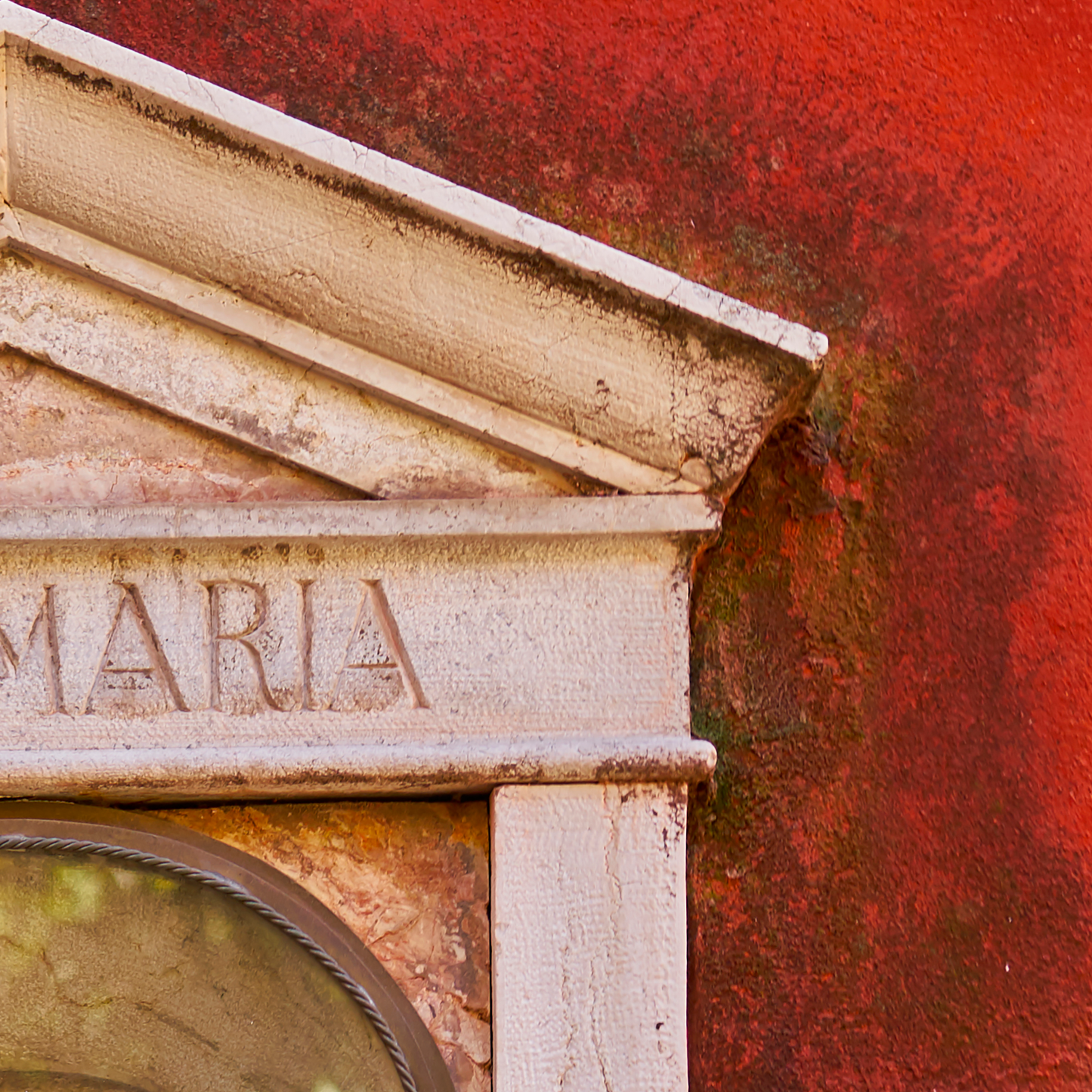 Stone architectural detail with 'MARIA' engraved on a red background