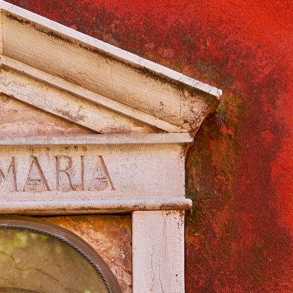 Stone architectural detail with 'MARIA' engraved on a red background
