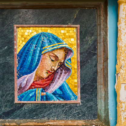 Mosaic artwork of a religious figure with a blue headscarf on a dark stone background