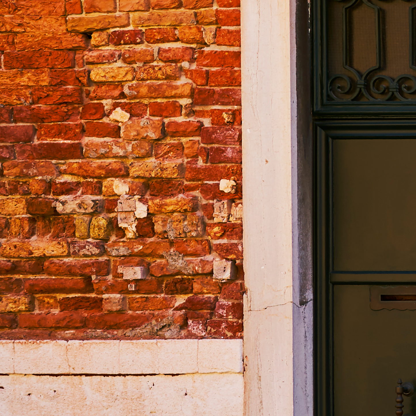 Close-up of a textured brick wall with a door on the right.