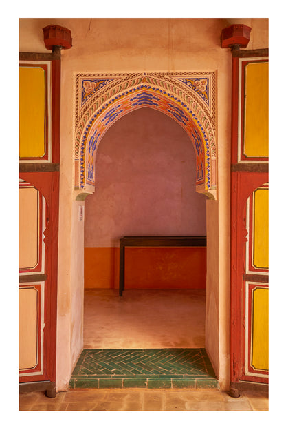 Decorative archway with colorful tiles in a room with a table and chair. Marrakesh Morocco