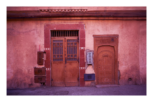 Traditional wooden doors on a pinkish-brown wall with decorative elements in Marrakesh Morocco