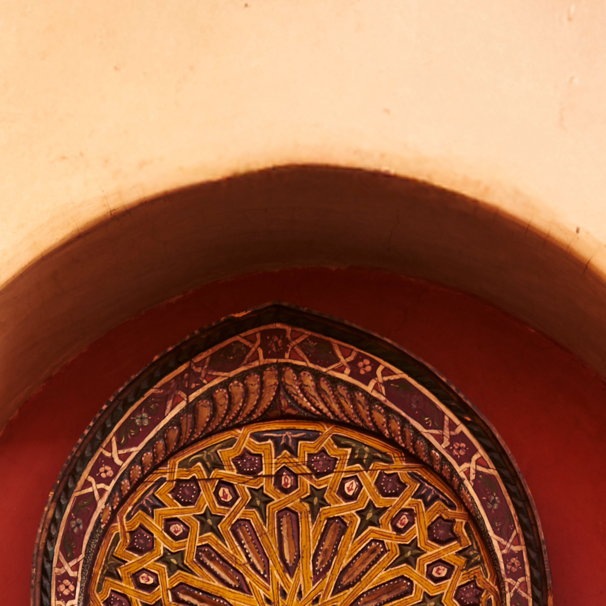 Decorative arch with intricate patterns in a warm-toned setting