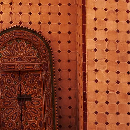 Decorative wooden door with intricate patterns on a textured wall.