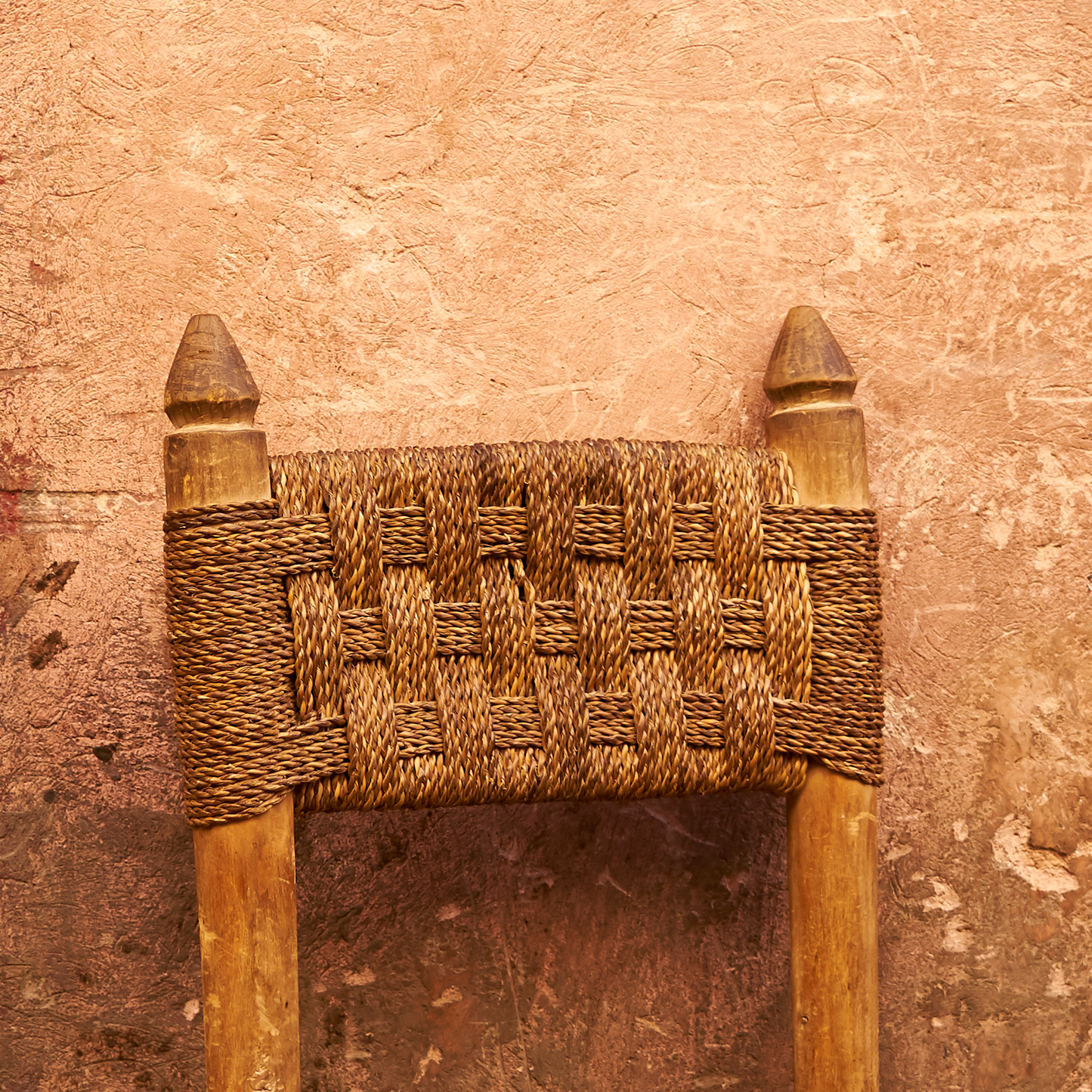 Woven wooden chair backrest against a textured brown background