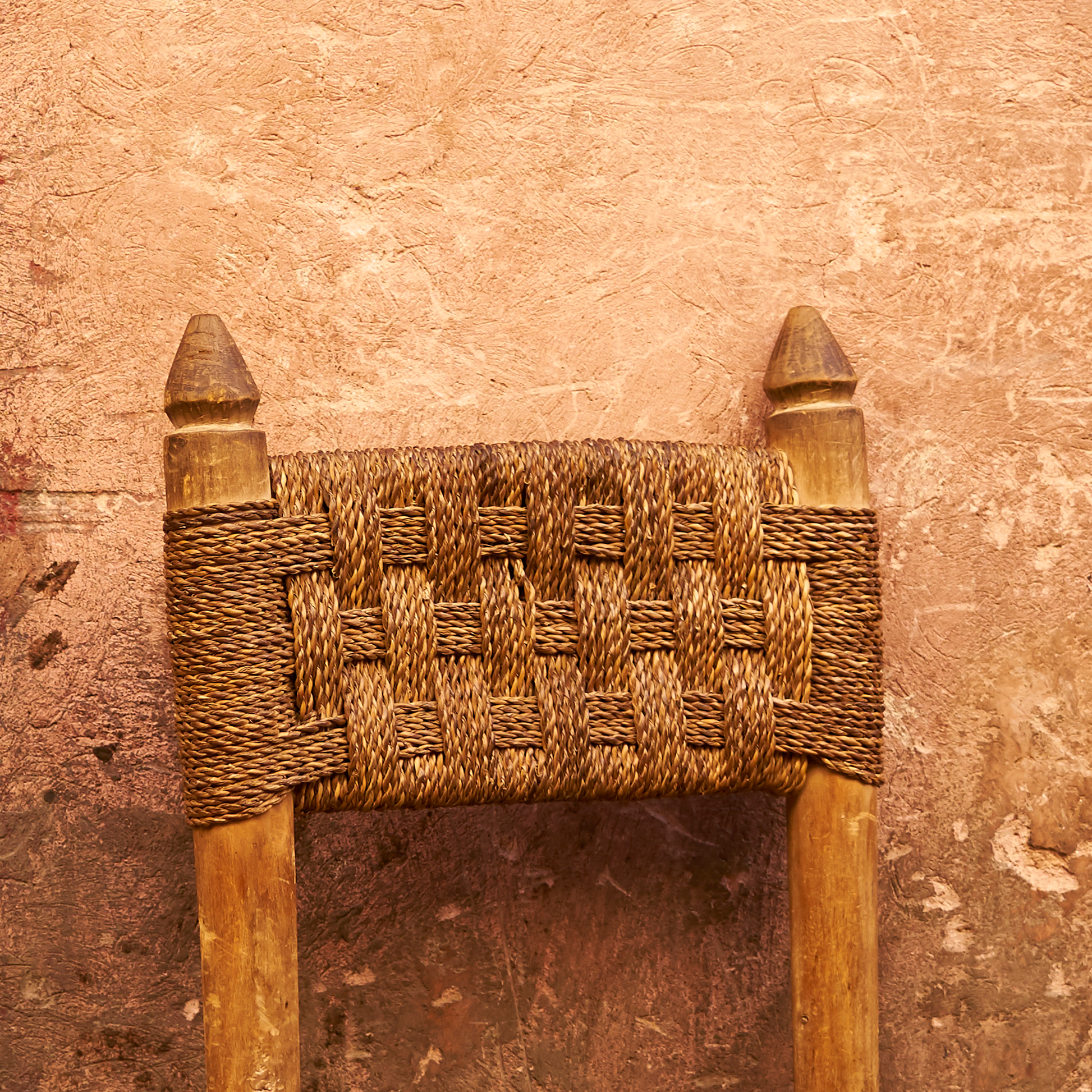 Woven wooden chair backrest against a textured brown background