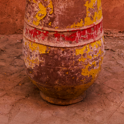 Rust-colored ceramic pot with yellow and red patches on a textured surface