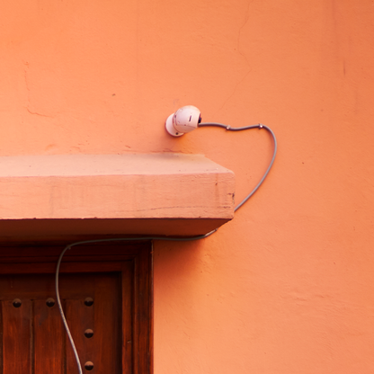 Small white device attached to an orange wall with a wooden shelf below.