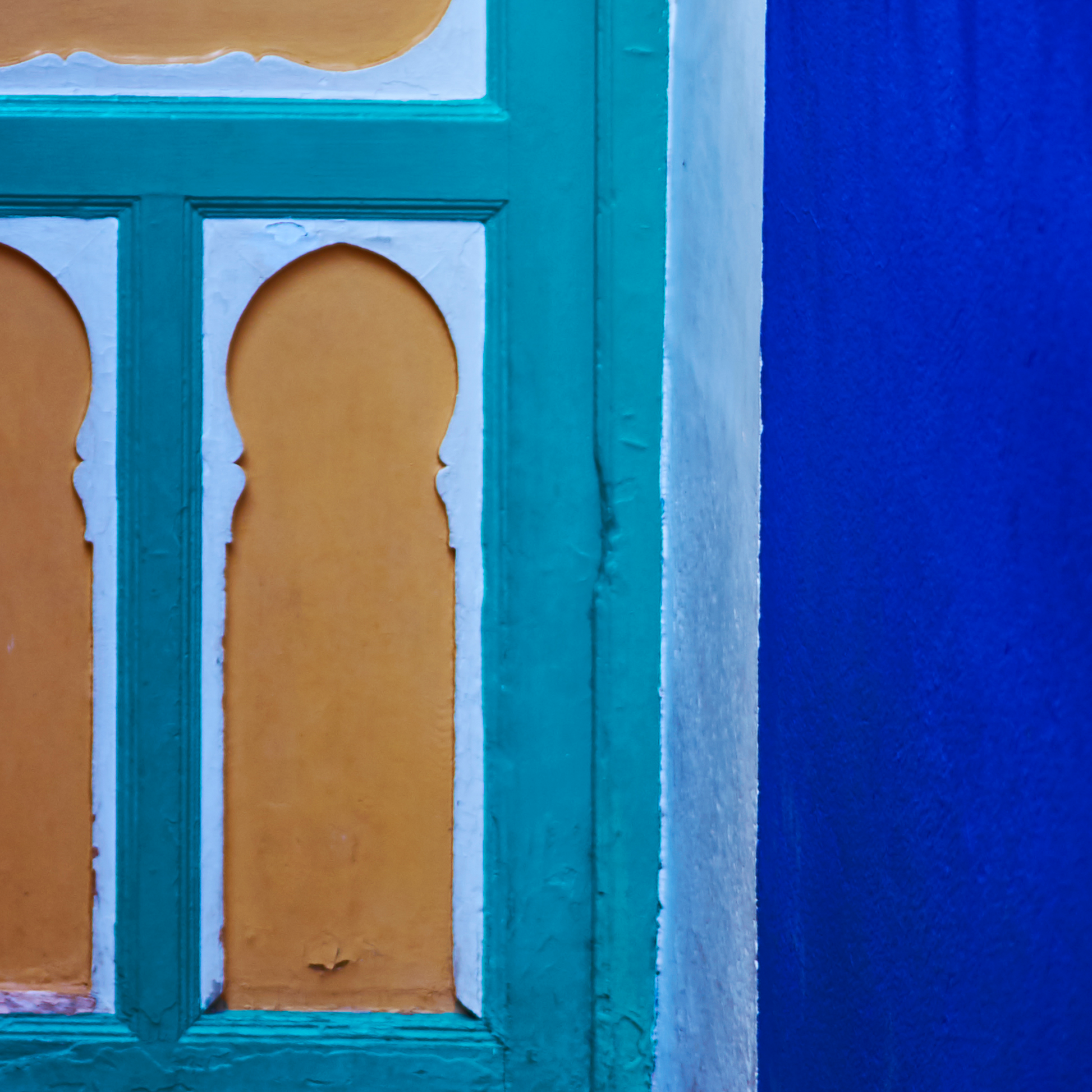 Close-up of a teal-framed wooden door with a blue wall in the background