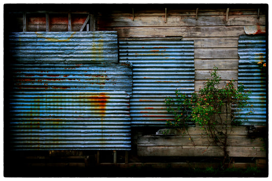 Rustic building with corrugated metal shutters and wooden walls.