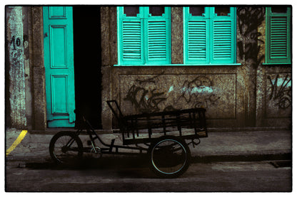 Graffiti-laden stone wall with green shutters and shopping bike in Rio de Janeiro street scene