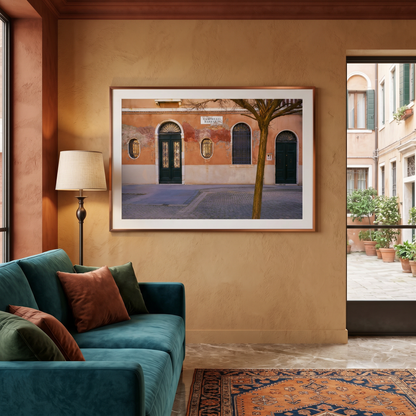 Living room with teal sofa, colorful rug, and framed artwork of a street scene.
